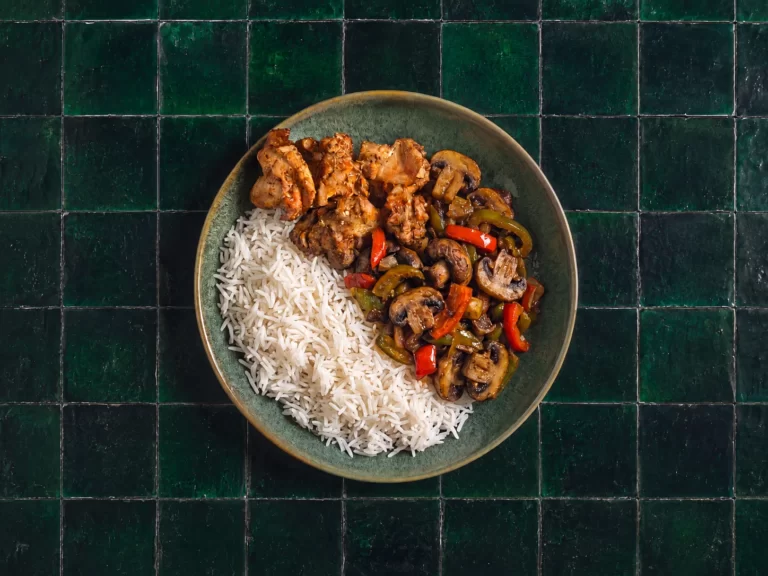 Geurige kip biryani met gegrilde champignons en met kruidnagel gekruide rijst.