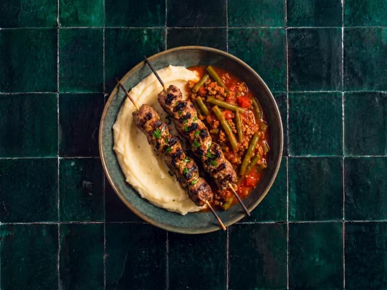 Kruidige kebabspiesen met sperziebonen in rode jus en aardappelpuree.